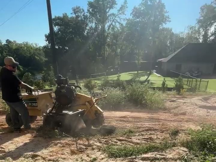 An ETX Valley operator walking the stump grinder across freshly cleared ground on a sunny lot.